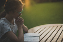 a young woman reading and praying over a Bible 