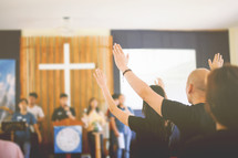 people with hands raised during a worship service 