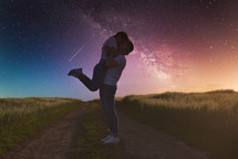 Silhouettes of a young couple in love under the starry sky with milky way.
