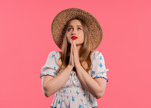 Young woman praying, begs to apologize her, she is guilty. Pink background. Hopeful prayer girl asking someone satisfy her desires, help with. High quality