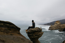 a woman sitting on a rock peak 