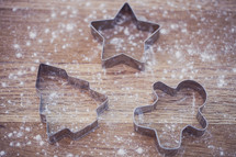 flour on a table and cookie cutters 