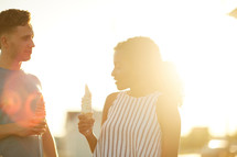 a man and a woman eating ice cream at sunset 