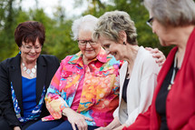 elderly women sitting on a park bench talking