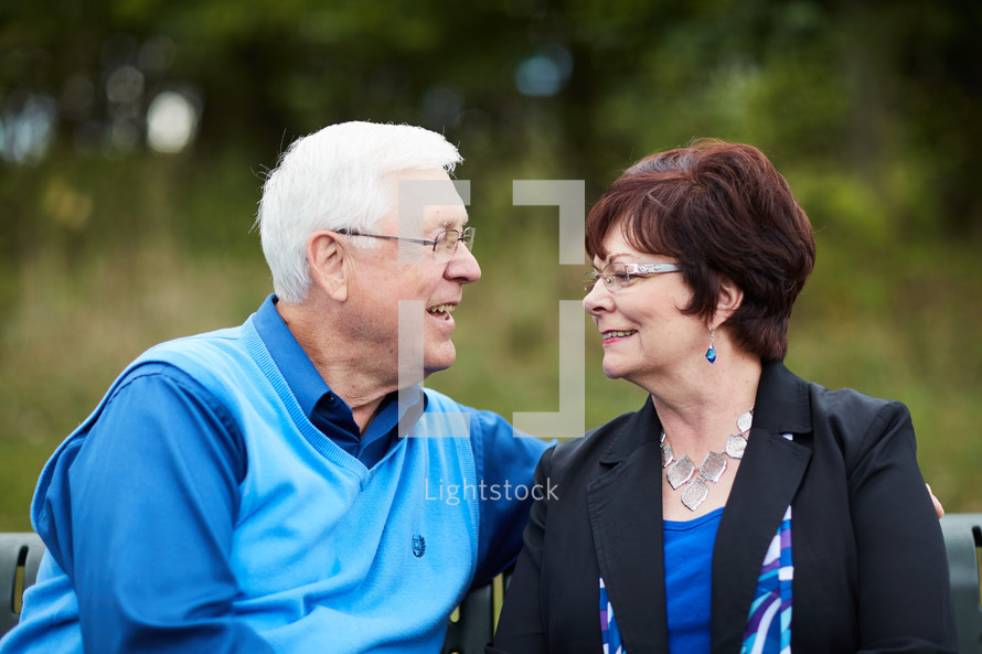  elderly couple sitting on a park bench 