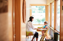 a mother feeding her daughter in a highchair 