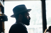 side profile of a man with a thick beard and hat 