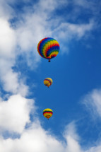 3 colorful hot air balloons ascending into the blue sky