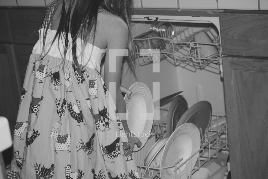 a little girl loading a dishwasher 