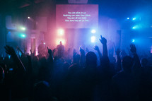 projection screen and raised hands at a contemporary worship service 