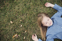 a little girl lying in the grass with closed eyes 