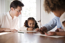 children coloring at the kitchen table with mom and dad 