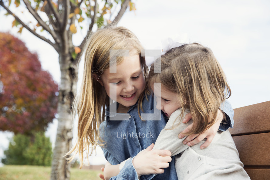 sisters hugging outdoors 