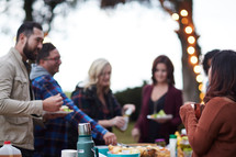 friends gathered around a table outdoors getting food in fall 