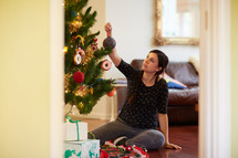 a woman decorating a Christmas tree