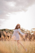 a young woman dancing in a field of tall grass 