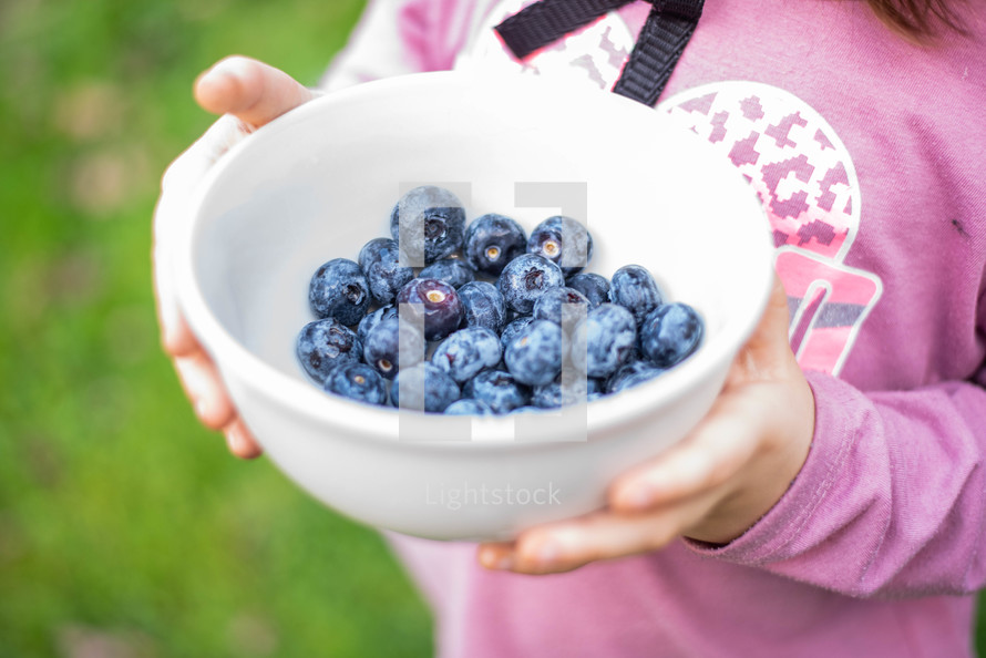 a girl holding a bowl of blueberries 