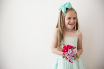 portrait of a giggling little girl holding flowers.