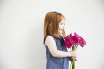 portrait of a red-headed little girl holding flowers.