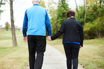 elderly couple walking holding hands 