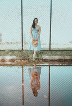 woman in a dress holding a hat and reflection in water 