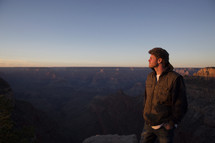a man standing at the top of a canyon at sunset 