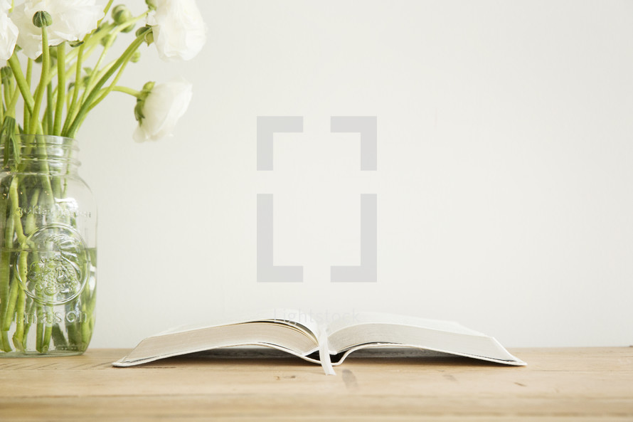white flowers in a vase and open Bible 