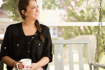woman on a porch swing with a Bible and coffee mug