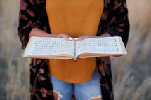 a woman standing in a field with sheet music 