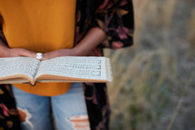a woman standing in a field with sheet music 