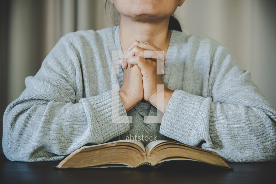 Asian woman praying with her Bible and hands clasped
