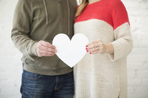 couple holding a paper heart cutout