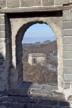 Chinese mountainside seen through an arched window at the Great Wall of China