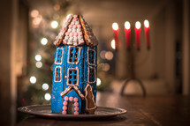 a gingerbread house and bokeh candlelight and Christmas tree lights in the background 