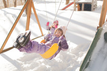 kids on a backyard swings in the snow 