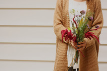 a woman holding a fall bouquet 