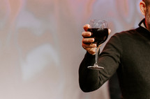 Man holding up a glass of wine during communion.