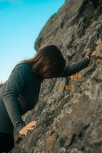 Rock climbing lady, woman mountain climbing wearing a long sleeve sports shirt, gripping rocks, bouldering outdoor sports and activities