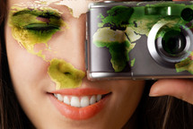 Smiling model with global map on her face making a photo using digital camera