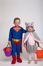 children dressed up for Halloween holding buckets of candy 
