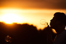 silhouette of a man blowing bubbles 