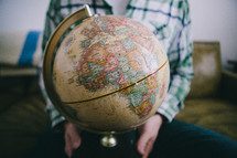 A man sits holding a globe.