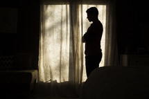 silhouette of a man standing in front of a window 