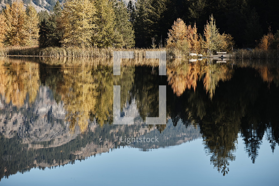 mountain and fall foliage reflecting on lake water 