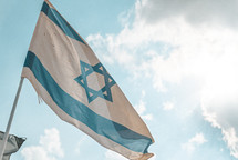 The flag of Israel against blue sky with clouds