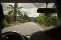 vehicle driving down a road lined with palm trees 