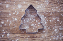 flour on a table and a Christmas tree cookie cutter