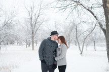 a couple kissing outdoors in the snow 