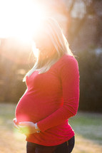 portrait of a pregnant woman standing in sunlight 