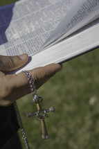 hands holding a cross and a Bible